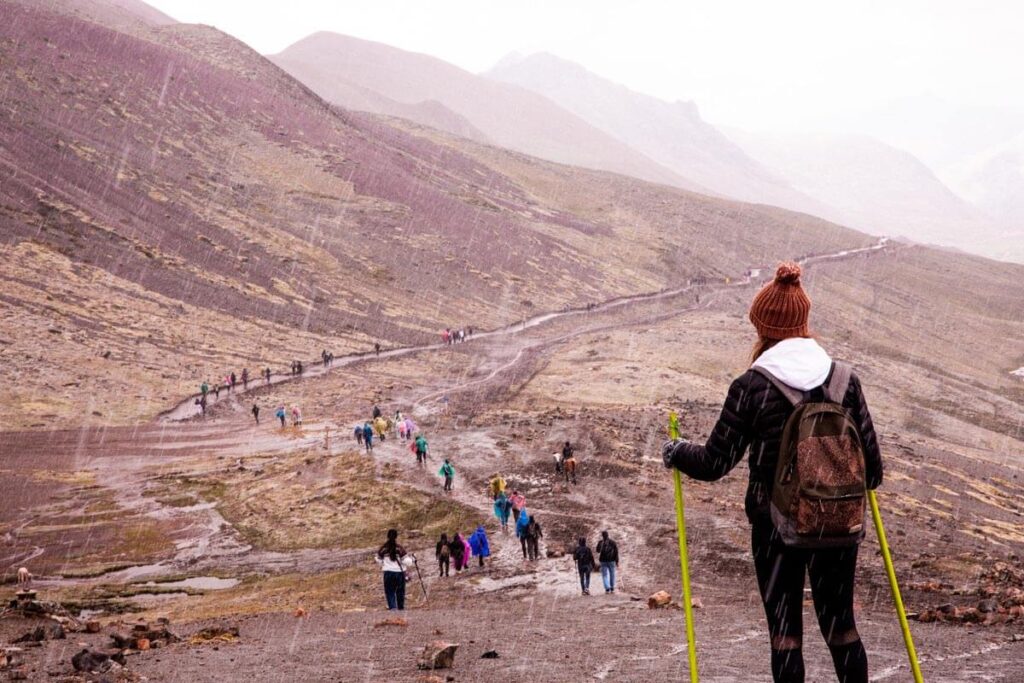 woman with hiking poles trekking in the rain