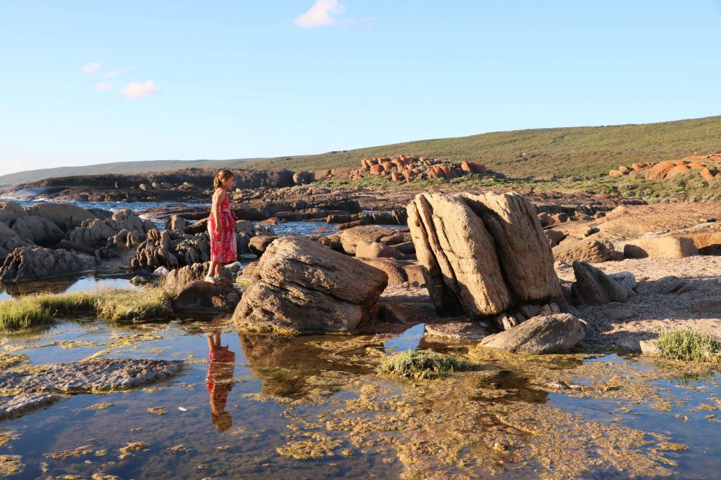 A little kid walking across stones in the water