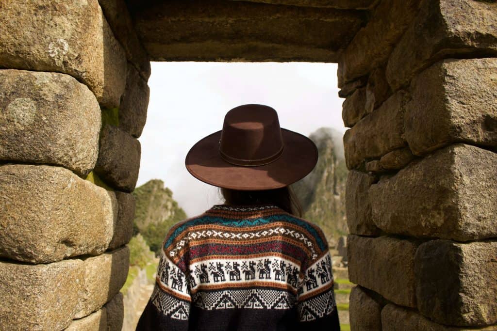 person with hat walking through entrance at Machu Picchu