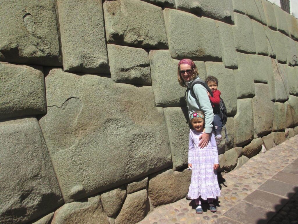 Mother with kids in front of Inca stones in Cusco