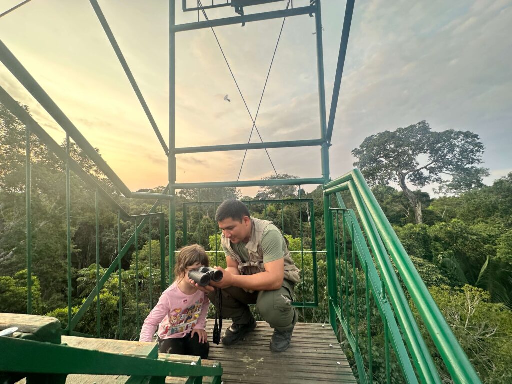 Guide holding binoculars for a little girl so she can look through