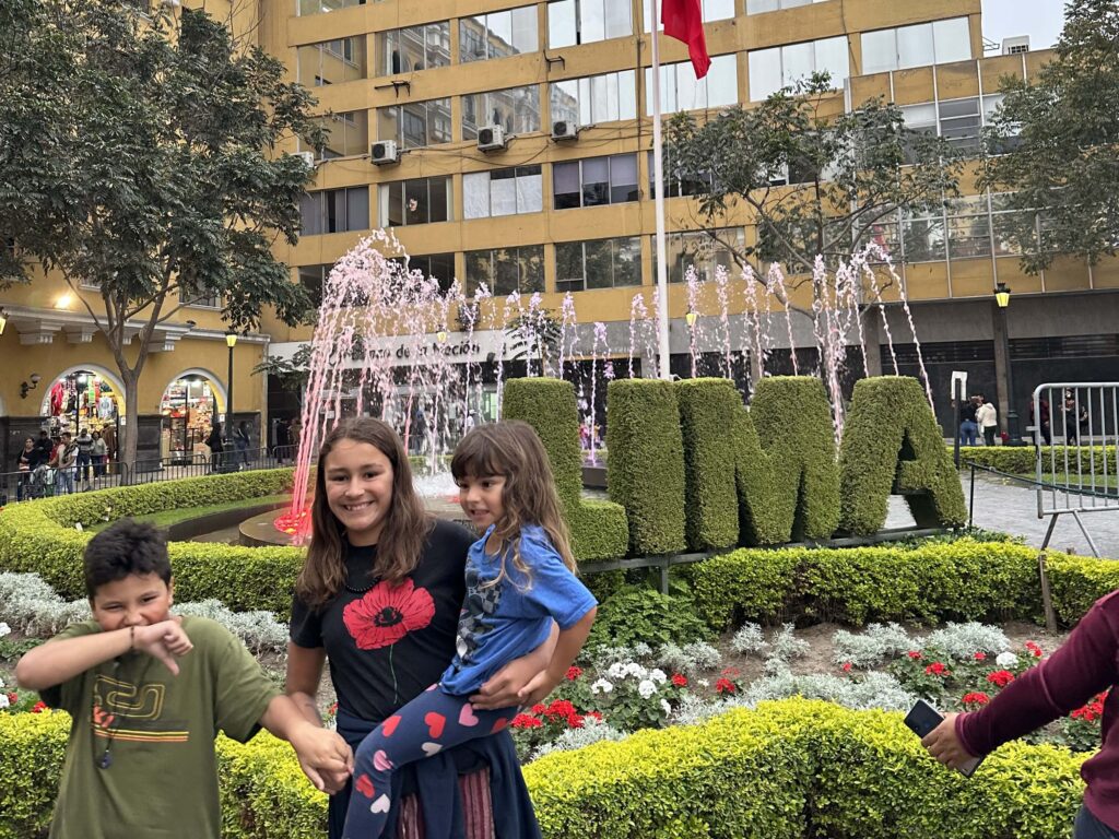 three kids in front of Lima sign